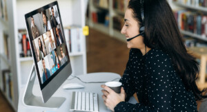 Frau mit Headset am PC im Online-Meeting