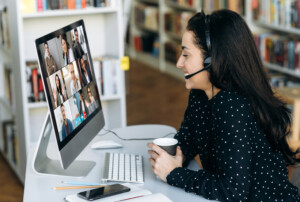 Frau mit Headset am PC im Online-Meeting