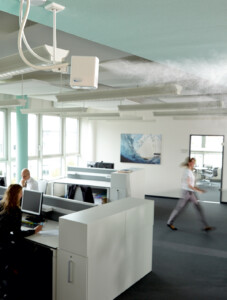 Offenes Büro mit drei Personen und Luftbefeuchter an der Decke, der Dampf ausstößt