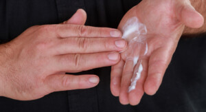 Eine Hand die Creme in einer anderen Hand verreibt.