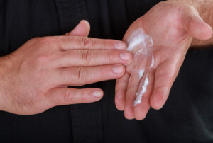 Eine Hand die Creme in einer anderen Hand verreibt.