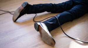 Detailaufnahme der unteren Beine (ab dem Knie) einer am Boden liegenden Person mit einem Kabel unter dem Schienbein und einem über der Wade.