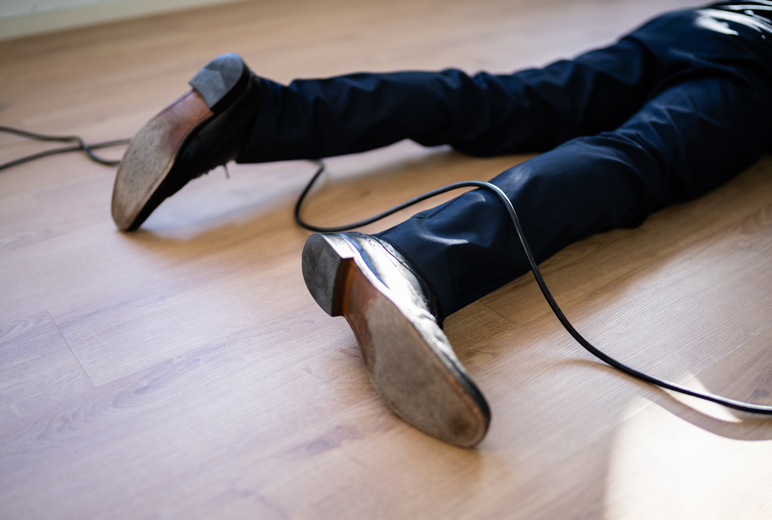 Detailaufnahme der unteren Beine (ab dem Knie) einer am Boden liegenden Person mit einem Kabel unter dem Schienbein und einem über der Wade.