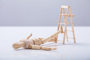 Eine Holzfigur ist von einer Holzleiter gefallen.