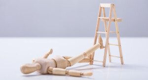 Eine Holzfigur ist von einer Holzleiter gefallen.