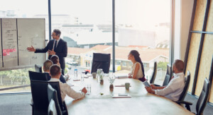 Ein Mann hält einen Vortrag vor 5 Personen in einem Meeting.
