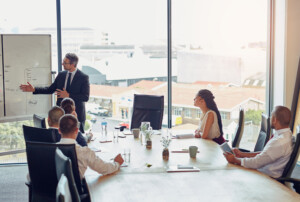 Ein Mann hält einen Vortrag vor 5 Personen in einem Meeting.