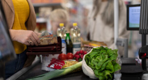 Eine Frau bezahlt bar ihren Einkauf im Supermarkt.