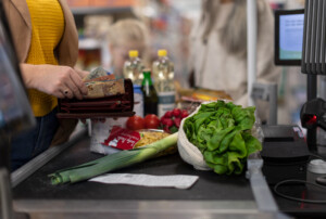Eine Frau bezahlt bar ihren Einkauf im Supermarkt.