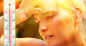 Eine verschwitzte Frau wischt sich unter grellem Sonnenlicht die Stirn, während ein Thermometer am Bildrand Temperaturen über vierzig Grad Celsius anzeigt.